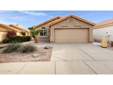 Tan house with tile roof, two-car garage, and desert landscaping at 2023 E Glenhaven Dr, Phoenix, AZ 85048