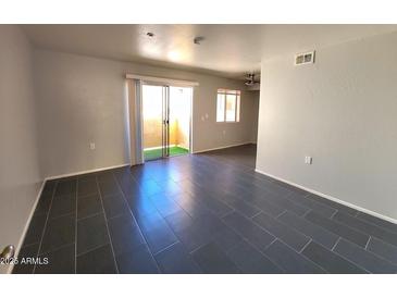 Open living room featuring tile flooring, neutral walls, and access to a patio via sliding glass doors at 12221 W Bell Rd # 259, Surprise, AZ 85378