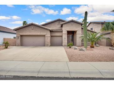 Charming single-story home featuring a three-car garage and desert landscaping with cacti and gravel at 1699 E Hearne Way, Gilbert, AZ 85234