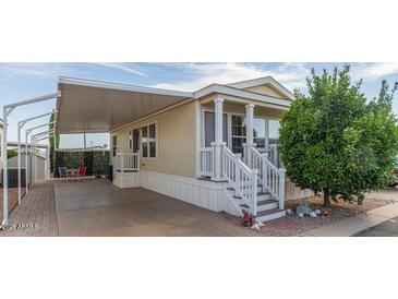 Tan mobile home with covered patio, white railing, and landscaping at 8700 E University Dr # 1315, Mesa, AZ 85207