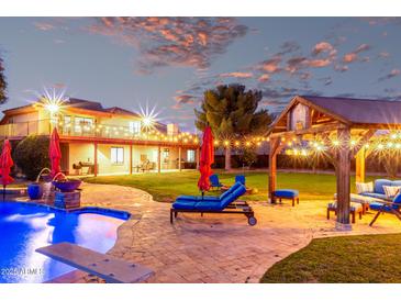 Outdoor living at its finest with a pool, lounge chairs, and a covered patio with string lights in a spacious backyard at 17645 E Stacey Rd, Queen Creek, AZ 85142