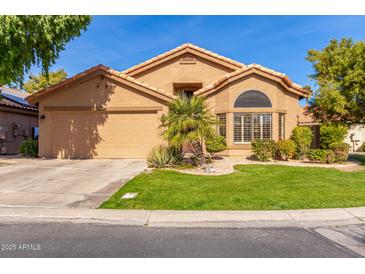 Tan house with a two-car garage and palm tree landscaping at 9428 W Taro Ln, Peoria, AZ 85382