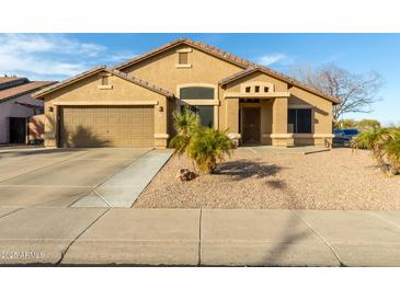 Single-story house with tan exterior, two-car garage, and desert landscaping at 8642 W Harmony Ln, Peoria, AZ 85382