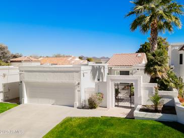 Stunning exterior of home features two-car garage, gated courtyard, and a palm tree at 10041 N 52Nd Pl, Paradise Valley, AZ 85253