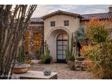 Stunning stone exterior with arched entryway and desert landscaping at 27256 N 97Th Pl, Scottsdale, AZ 85262