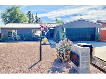 Charming single-story home with desert landscaping, gray facade, and a black garage door at 6307 E Gelding Dr, Scottsdale, AZ 85254