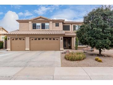 Two-story house with tan exterior, three-car garage, and desert landscaping at 2551 E Saratoga St, Gilbert, AZ 85296