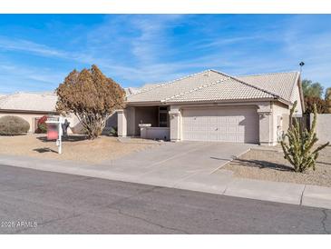 Single-story house with a beige exterior, two-car garage, and desert landscaping at 2605 N 133Rd Ave, Goodyear, AZ 85395