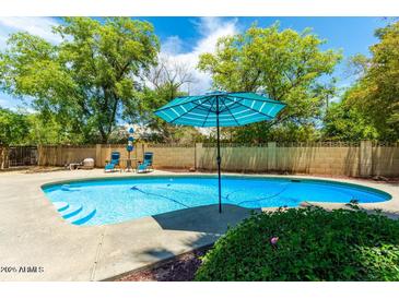 Inviting kidney-shaped pool with a patio and umbrella; perfect for relaxation at 4543 W Lane Ave, Glendale, AZ 85301