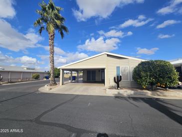 Tan mobile home with carport, landscaping, and a cactus decoration at 650 N Hawes Rd # 4820, Mesa, AZ 85207