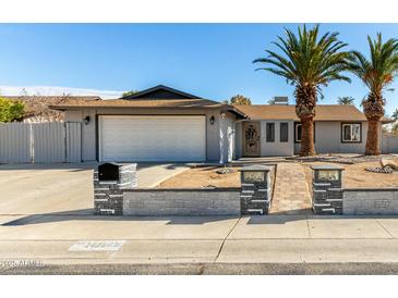 Ranch style home with gray exterior, two-car garage, and landscaped front yard at 14219 N 51St Dr, Glendale, AZ 85306