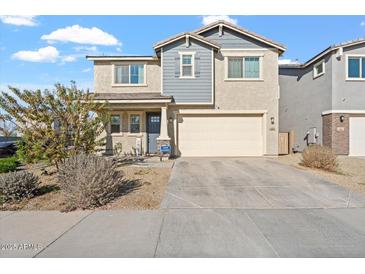 Two-story house with gray siding, beige garage door, and landscaping at 10994 W Mckinley St, Avondale, AZ 85323