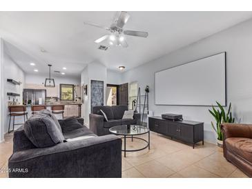 Open living room with adjacent kitchen and a large screen at 44783 W Alamendras St, Maricopa, AZ 85139