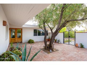 Brick courtyard with a large olive tree and brick fountain at 8521 N 15Th Dr, Phoenix, AZ 85021