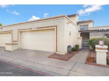 Tan two-story condo building with attached garage and gated entryway at 10836 N 29Th Ave, Phoenix, AZ 85029