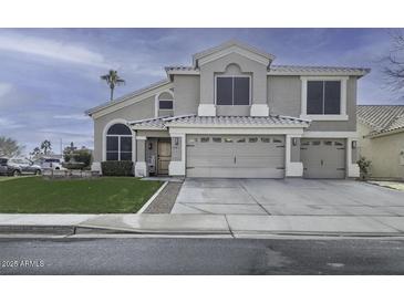 Two-story house with a large driveway, landscaped lawn, and a three-car garage at 647 S Cholla St, Gilbert, AZ 85233