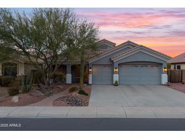 Gray two-story house with a three-car garage and nicely landscaped front yard at 12522 W Llano Dr, Litchfield Park, AZ 85340