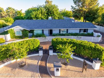 Charming single-story home with a manicured front yard, white picket fence, and lush greenery at 5249 E Thunderbird Rd, Scottsdale, AZ 85254