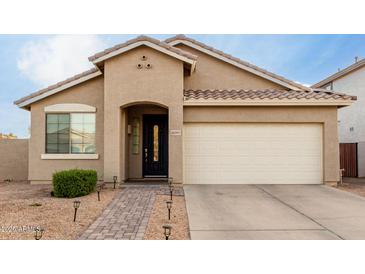 One-story house with tan exterior, two-car garage, and landscaped front yard at 15207 W Windward Ave, Goodyear, AZ 85395