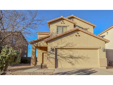 Two-story house with tan siding, a two-car garage, and mature trees in the front yard at 35706 W Costa Blanca Dr, Maricopa, AZ 85138