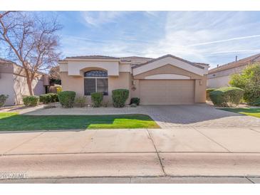 Single-story home with tan exterior, landscaped yard, and a two-car garage at 8687 E Tuckey Ln, Scottsdale, AZ 85250