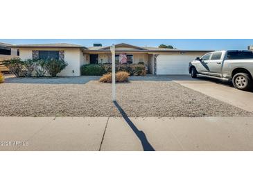 Charming single-story home featuring a two-car garage, rock landscaping, and mature bushes at 5501 E Dallas St, Mesa, AZ 85205
