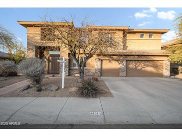 Inviting two-story home featuring a three-car garage and desert landscaping at 6102 E Sonoran Trl, Scottsdale, AZ 85266