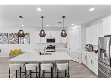 Modern kitchen with white cabinets, large island, and stainless steel appliances at 10037 E Rubidium Ave, Mesa, AZ 85212