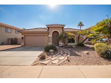 One-story house with a tan exterior, arched entryway, and landscaped front yard at 15839 W Calavar Rd, Surprise, AZ 85379