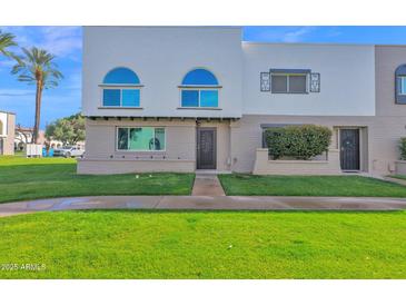 Inviting two-story townhome with a well-maintained lawn and charming architectural details at 2912 E Clarendon Ave, Phoenix, AZ 85016