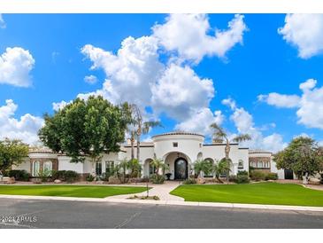 Stunning white stucco home with a circular driveway and lush landscaping at 3447 E Kenwood St, Mesa, AZ 85213