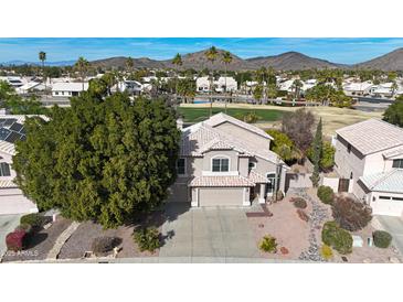 Aerial view of two story house with a desert landscape, golf course, and mountain background at 6282 W Rose Garden Ln, Glendale, AZ 85308