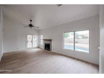 Bright living room features a fireplace, wood-look floors, and sliding doors to a pool at 18429 N 16Th Way, Phoenix, AZ 85022