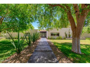 Inviting home featuring a lush front yard with desert landscaping and mature trees at 3601 N 55Th Pl, Phoenix, AZ 85018