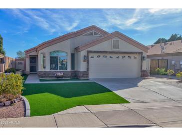 Charming single-story home featuring a manicured lawn, arched window and an attached two-car garage at 1041 N 91St Pl, Mesa, AZ 85207