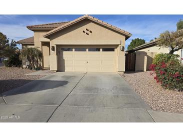 Tan home featuring a spacious two car garage and a large concrete driveway at 12558 W Jefferson St, Avondale, AZ 85323