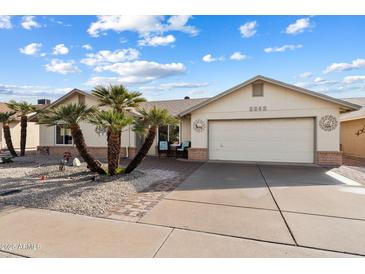 Single-story home with landscaped front yard, palm trees, and a two-car garage at 2242 Leisure World --, Mesa, AZ 85206