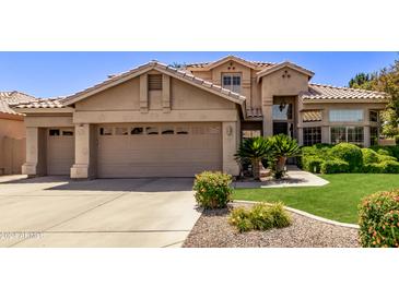 Two-story house with tan exterior, landscaped yard, and two-car garage at 302 S Laguna Dr, Gilbert, AZ 85233