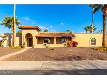 Spanish-style home with attractive landscaping and a covered entryway at 6030 E Crocus Dr, Scottsdale, AZ 85254