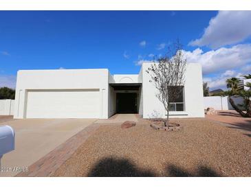 Single-story home with white exterior, two-car garage, and landscaping at 634 E Calavar Rd, Phoenix, AZ 85022