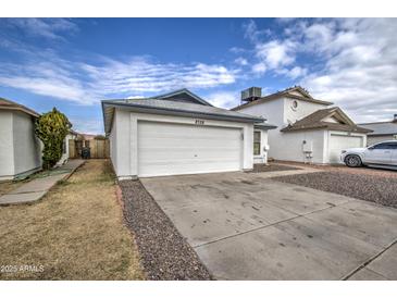 Front view of a single-story house with a white garage door and rock landscaping at 8728 W Vale Dr, Phoenix, AZ 85037