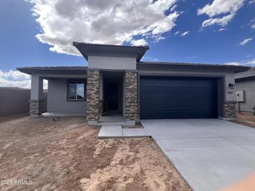 Charming single-story home with a dark blue garage door and complementary stone pillar accents at 20596 N 226Th Dr, Surprise, AZ 85387