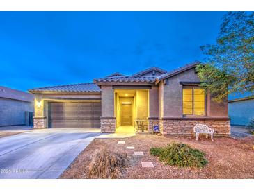 Exterior shot of single-story home with desert landscaping, and a two car garage at twilight at 23820 W Mobile Ln, Buckeye, AZ 85326