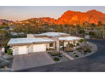 Modern home with a flat roof, desert landscaping, and a mountain backdrop at 4414 E Vermont S Ave, Phoenix, AZ 85018
