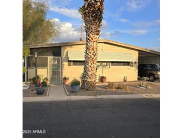 Tan single-wide manufactured home with mature palm tree in front at 11411 N 91St Ave # 80, Peoria, AZ 85345