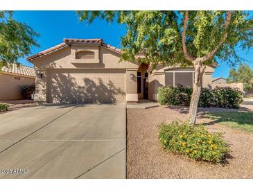 Tan house with two-car garage, landscaping, and driveway at 43726 W Carey Dr, Maricopa, AZ 85138