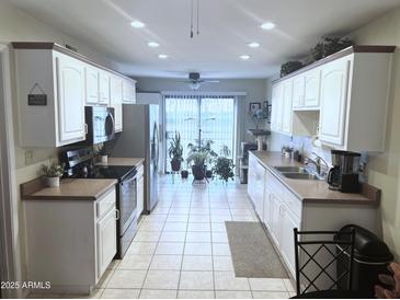 Bright kitchen featuring white cabinets, stainless appliances, and sliding glass doors to outdoor patio at 455 S Delaware Dr # 117, Apache Junction, AZ 85120