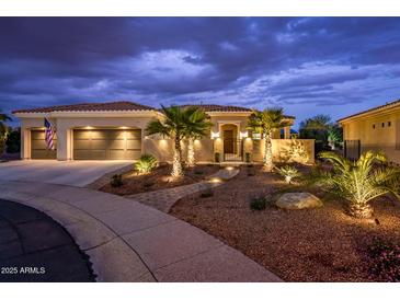 Stunning desert home exterior at night; landscaped yard, three-car garage, and attractive lighting at 13286 W Micheltorena Ct, Sun City West, AZ 85375