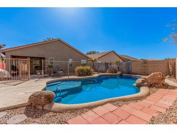 Backyard pool featuring a rock surround, brick pavers and partial fencing at 44520 W Windrose Dr, Maricopa, AZ 85138