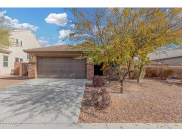 House exterior featuring a brown garage door, stone accents, and a well-manicured front yard at 3905 S 185Th Ln, Goodyear, AZ 85338